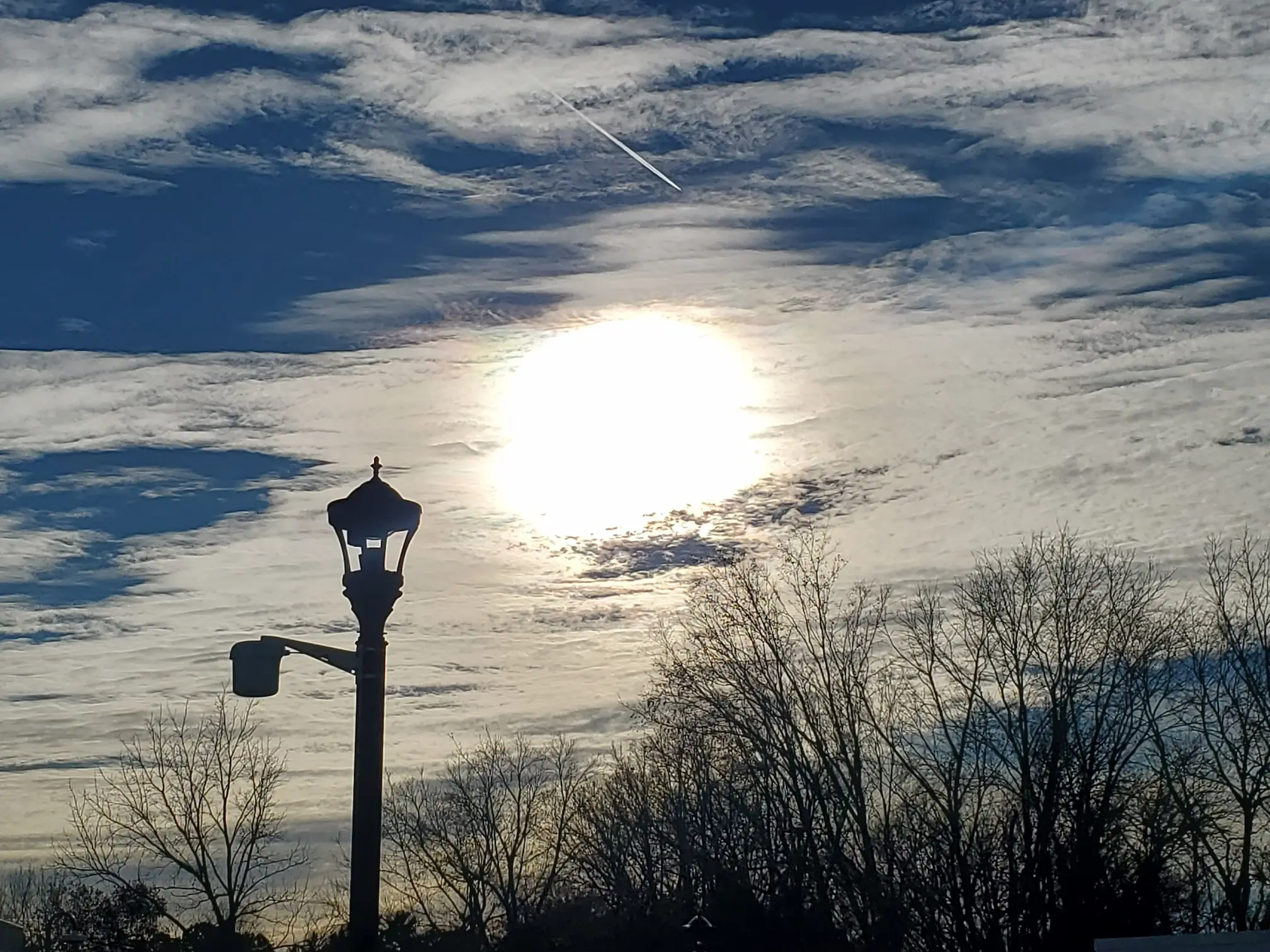 The sun rises in the background, with a street lamp in the foreground.